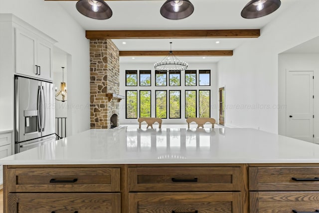 kitchen featuring beamed ceiling, light countertops, stainless steel refrigerator with ice dispenser, and white cabinets