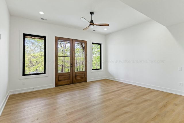 spare room featuring light wood-style floors, french doors, and baseboards