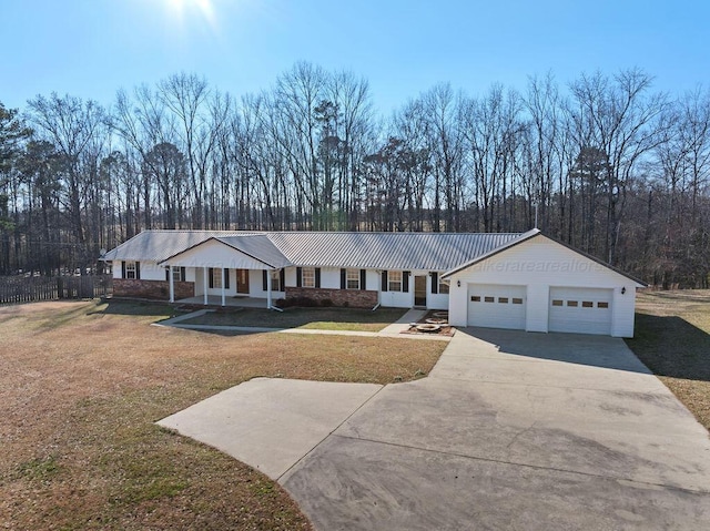 view of front of property featuring metal roof, a front yard, a garage, and concrete driveway