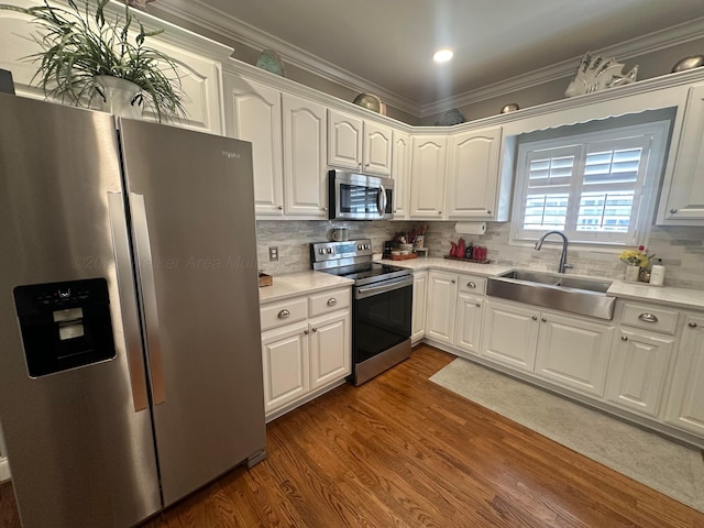 kitchen with appliances with stainless steel finishes, a sink, dark wood-style floors, white cabinetry, and light countertops