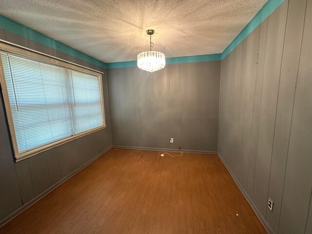 47 Hyche Rd, Cordova, AL 35550 - unfurnished room featuring wood finished floors, a chandelier, a textured ceiling, and baseboards