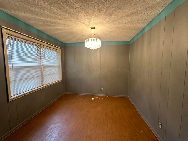 47 Hyche Rd, Cordova, AL 35550 - spare room featuring wood finished floors, a chandelier, a textured ceiling, and baseboards