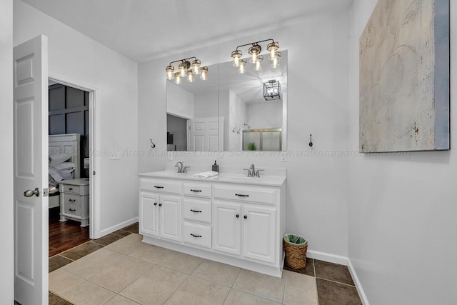 bathroom featuring double vanity, a stall shower, baseboards, tile patterned flooring, and a sink