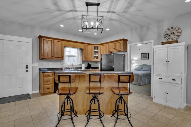 kitchen featuring brown cabinets, light tile patterned floors, a kitchen breakfast bar, and freestanding refrigerator