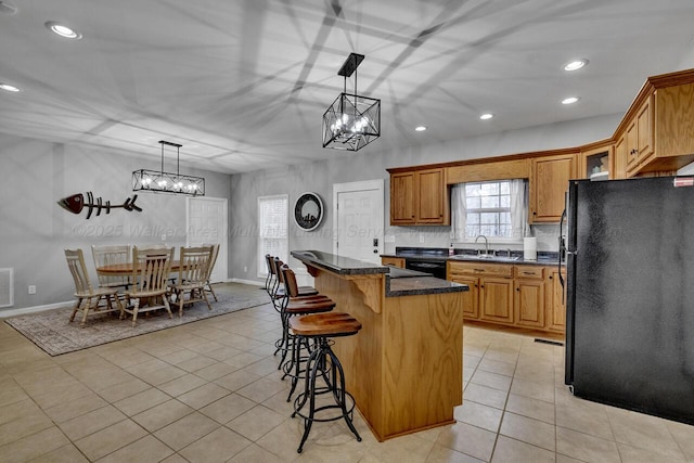 kitchen with light tile patterned floors, a kitchen island, a sink, black appliances, and a kitchen bar