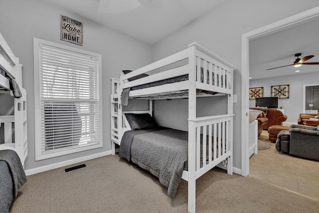 carpeted bedroom with baseboards, ceiling fan, visible vents, and tile patterned floors