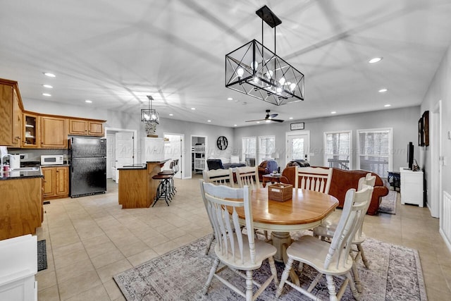 dining space with ceiling fan with notable chandelier, light tile patterned floors, and recessed lighting