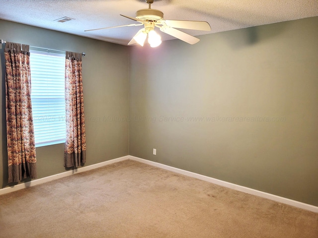 unfurnished room featuring visible vents, a ceiling fan, carpet floors, and a textured ceiling