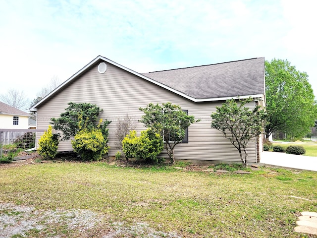 view of side of home featuring a lawn and a shingled roof