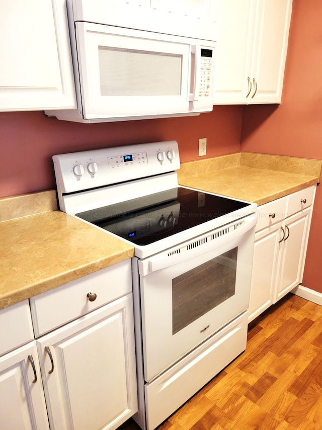 kitchen featuring white appliances, white cabinetry, light countertops, and light wood-style floors