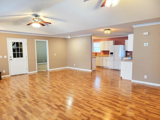 unfurnished living room with baseboards, light wood-style flooring, a sink, and a ceiling fan