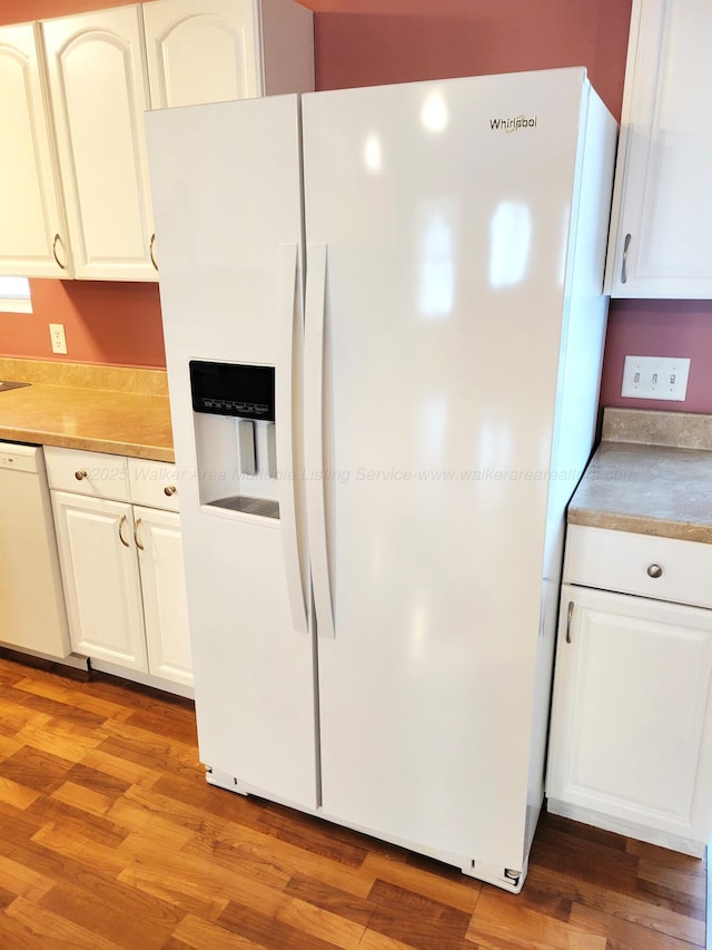 kitchen featuring white cabinetry, light countertops, light wood-type flooring, and white appliances