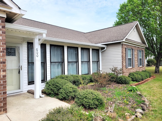 view of home's exterior with a shingled roof and brick siding