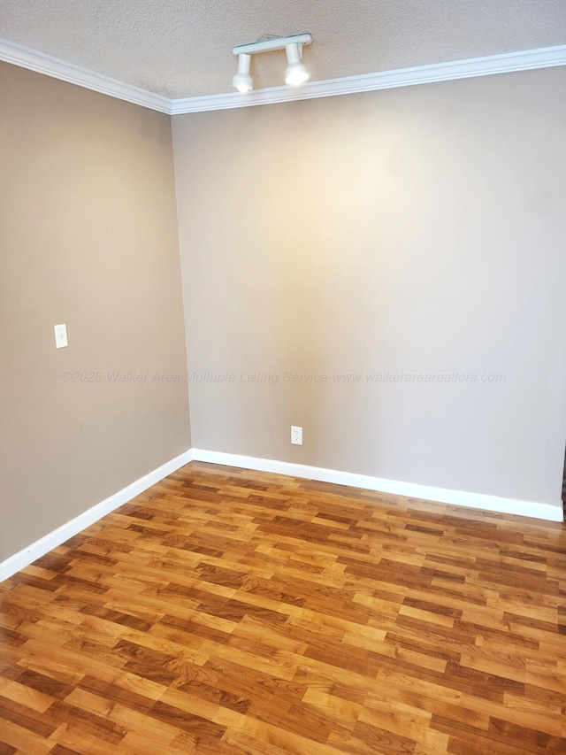 unfurnished room featuring light wood-type flooring, ornamental molding, baseboards, and a textured ceiling
