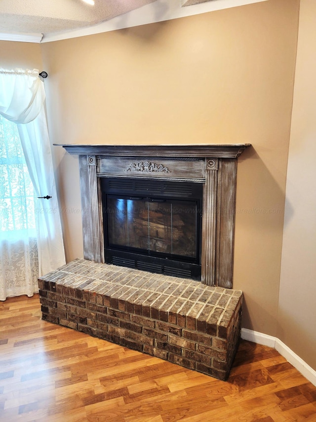 room details featuring baseboards, wood finished floors, and a brick fireplace