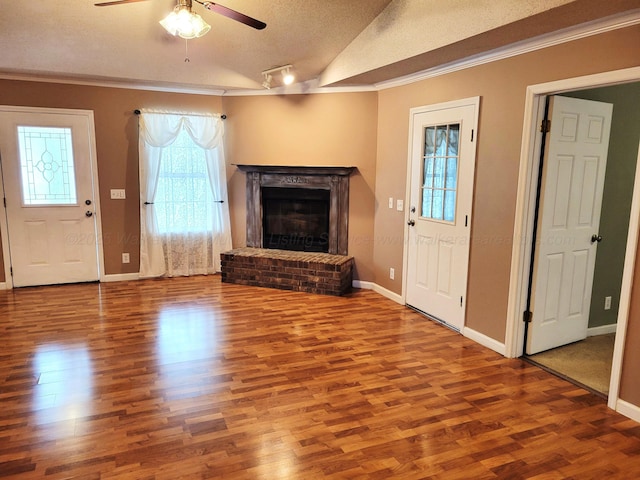 unfurnished living room with crown molding, baseboards, a fireplace, wood finished floors, and ceiling fan