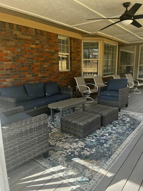 deck with an outdoor living space, a patio, and a ceiling fan