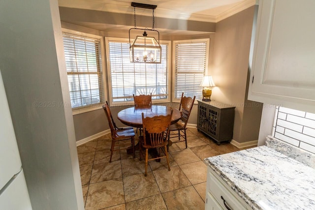 dining room featuring baseboards, ornamental molding, and a notable chandelier