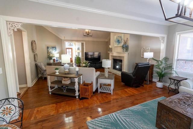 living area featuring a glass covered fireplace, baseboards, ornamental molding, and hardwood / wood-style floors