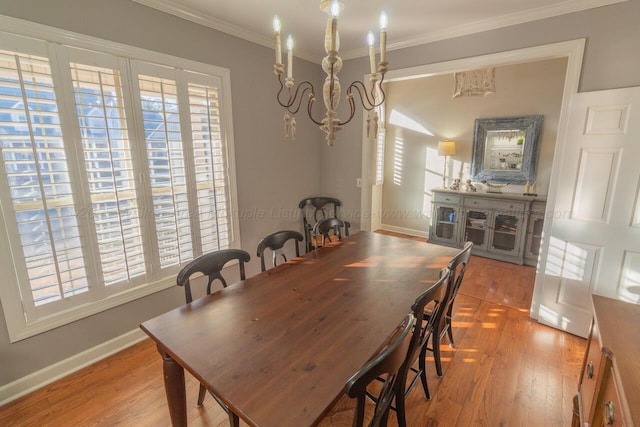 dining space featuring baseboards, wood finished floors, ornamental molding, and an inviting chandelier