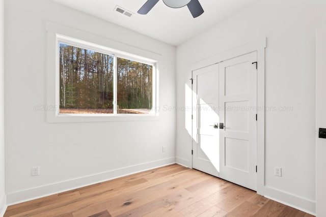 unfurnished bedroom featuring baseboards, visible vents, light wood-style floors, and a ceiling fan