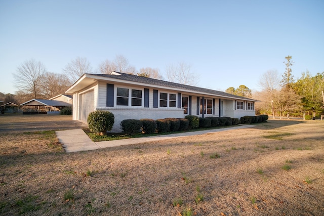 ranch-style house featuring an attached garage, brick siding, a front lawn, and driveway