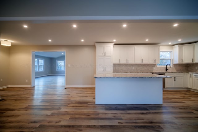 kitchen featuring dark wood-style flooring, white cabinets, backsplash, and light stone countertops
