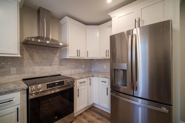 kitchen featuring white cabinets, wall chimney range hood, tasteful backsplash, and appliances with stainless steel finishes