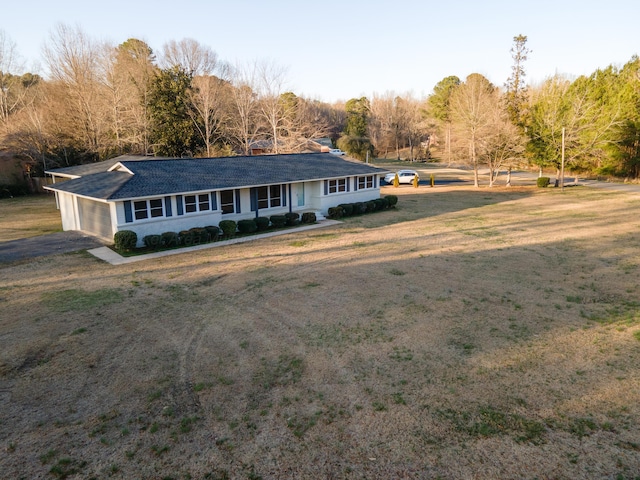 ranch-style home with driveway, a garage, roof with shingles, and a front yard