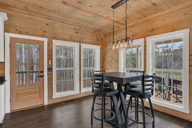 dining room with an inviting chandelier, wood ceiling, dark wood-style floors, wooden walls, and visible vents