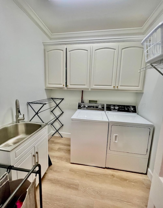 305 Chris Ln, Winfield, AL 35594 - laundry area featuring washing machine and dryer, crown molding, a sink, light wood-type flooring, and cabinet space