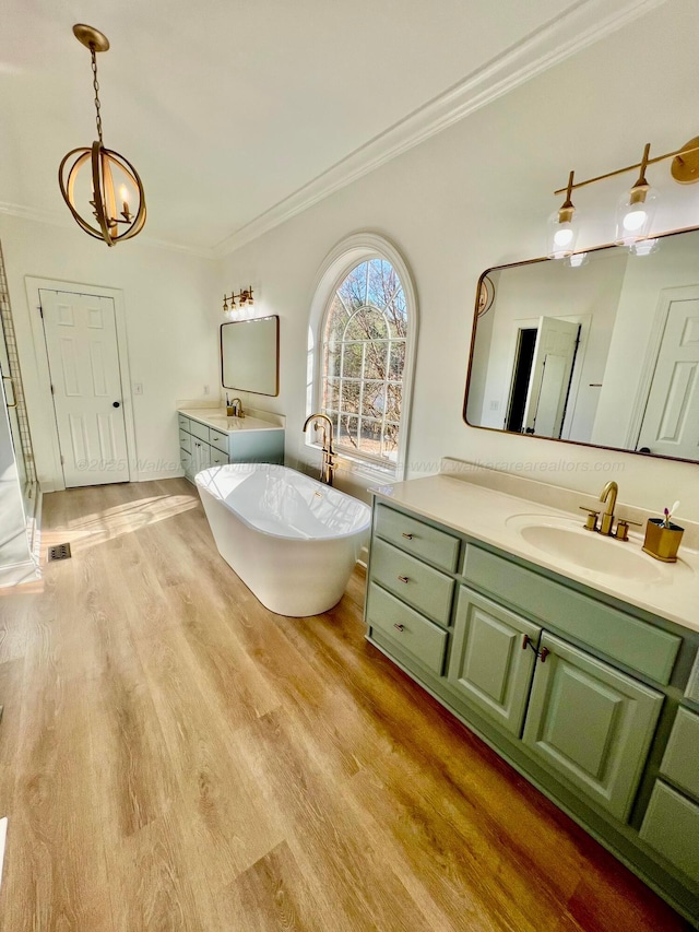 305 Chris Ln, Winfield, AL 35594 - full bathroom featuring ornamental molding, a sink, a freestanding bath, two vanities, and wood finished floors