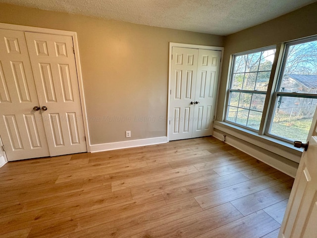 1532 SW Bay Ave, Birmingham, AL 35211 - unfurnished bedroom with a textured ceiling, light wood-type flooring, and two closets