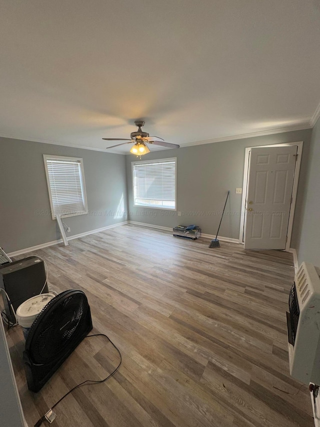 interior space featuring heating unit, a ceiling fan, baseboards, and wood finished floors