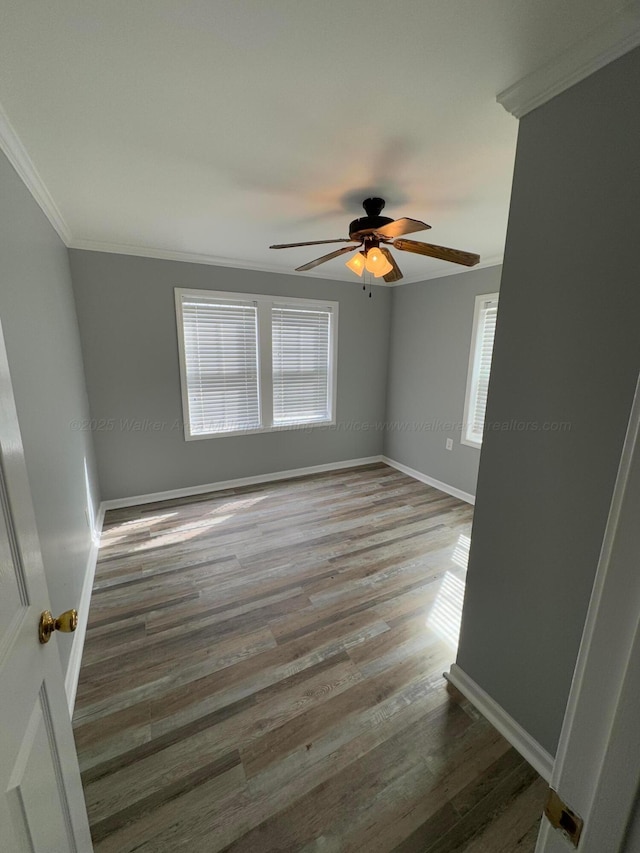 empty room with baseboards, ceiling fan, wood finished floors, and ornamental molding