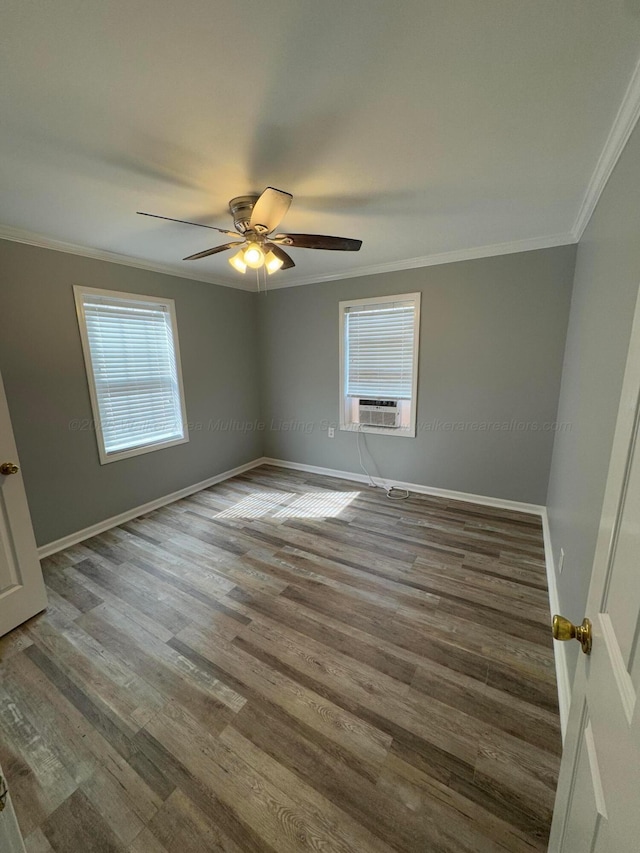 empty room featuring a wealth of natural light, crown molding, wood finished floors, and a ceiling fan
