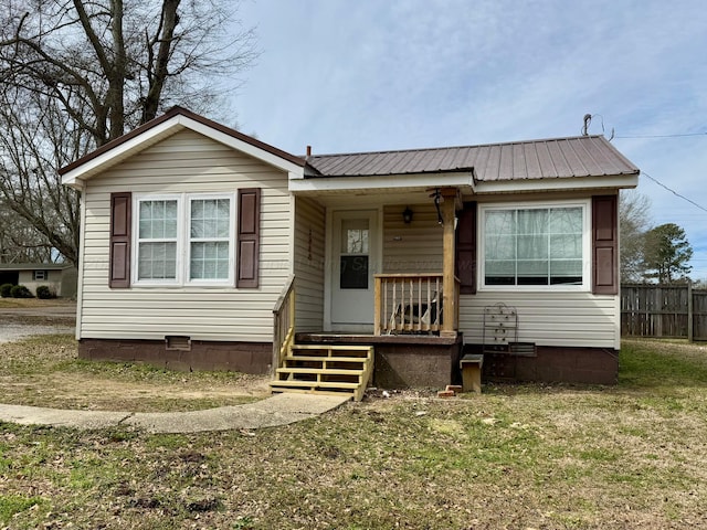 bungalow-style house with a porch, crawl space, fence, and metal roof