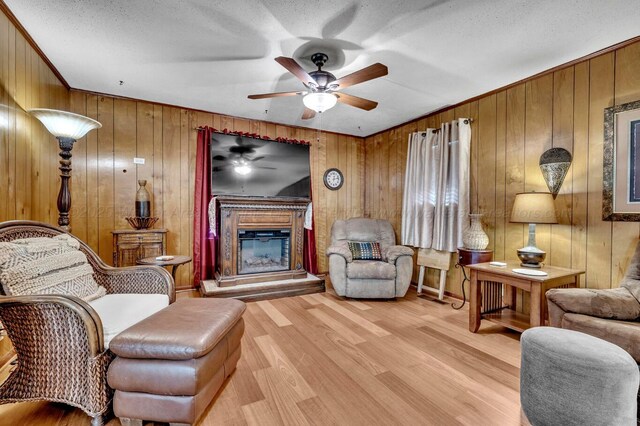 2555 Shady Rd, Adamsville, AL 35005 - living area featuring ceiling fan, a glass covered fireplace, wood finished floors, a textured ceiling, and wooden walls