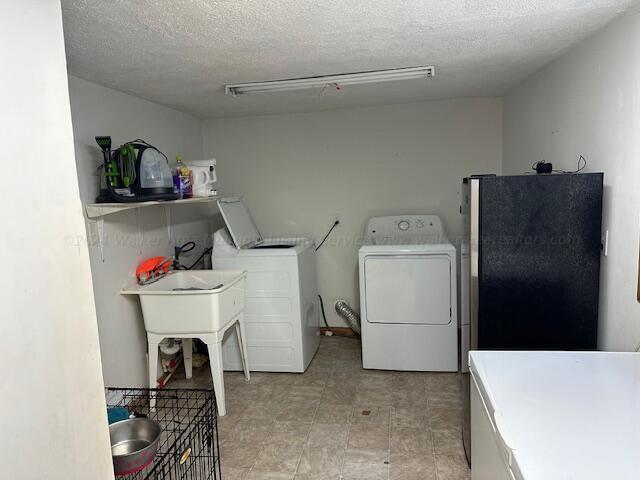 laundry area with washer and clothes dryer, laundry area, and a textured ceiling