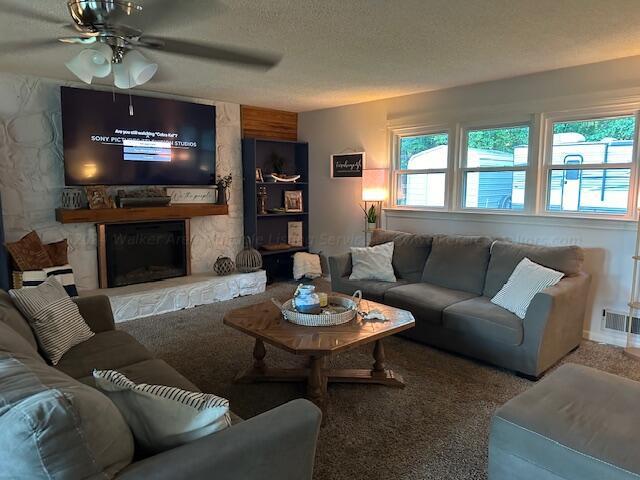 living area featuring a wealth of natural light, visible vents, a fireplace, and a textured ceiling