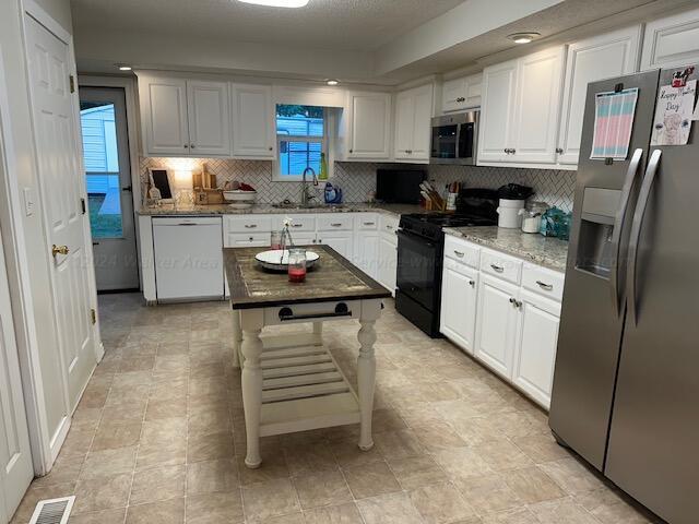 kitchen with visible vents, white cabinetry, a sink, and stainless steel appliances