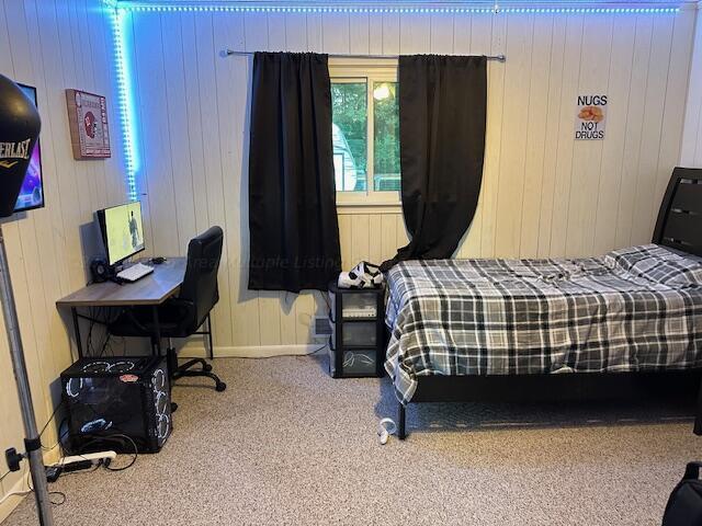 carpeted bedroom with wood walls