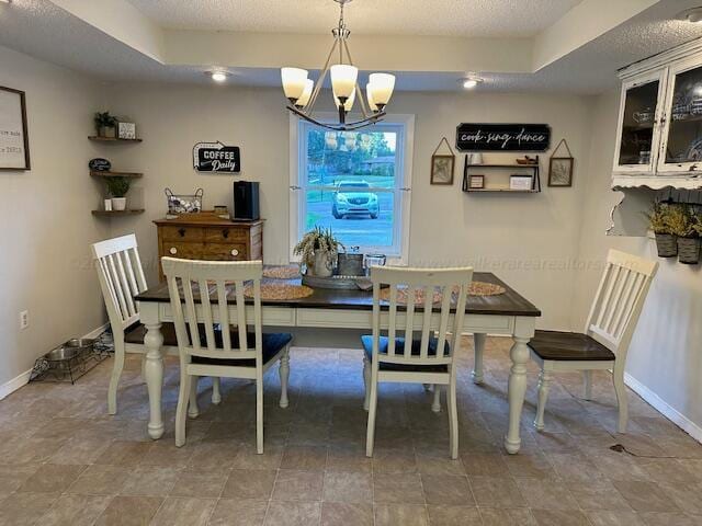 dining area featuring a notable chandelier, baseboards, and a textured ceiling