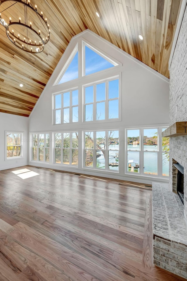 556 Sipsey Rock Rd, Crane Hill, AL 35053 - unfurnished living room featuring a water view, a large fireplace, high vaulted ceiling, a chandelier, and wooden ceiling