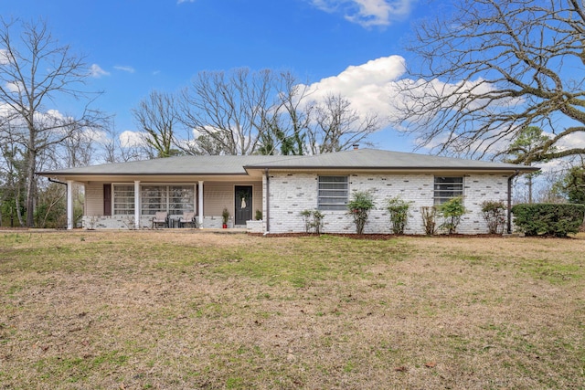 ranch-style house featuring covered porch and a front yard