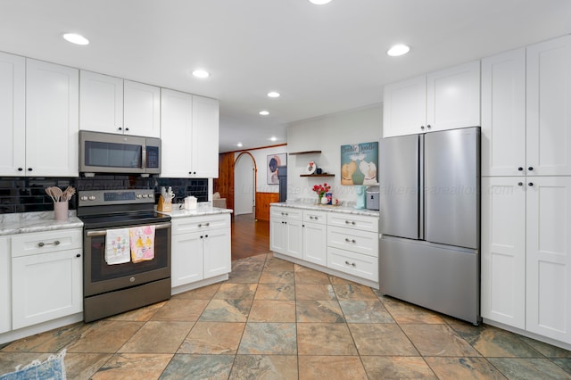 kitchen featuring appliances with stainless steel finishes, tasteful backsplash, light stone countertops, and white cabinets