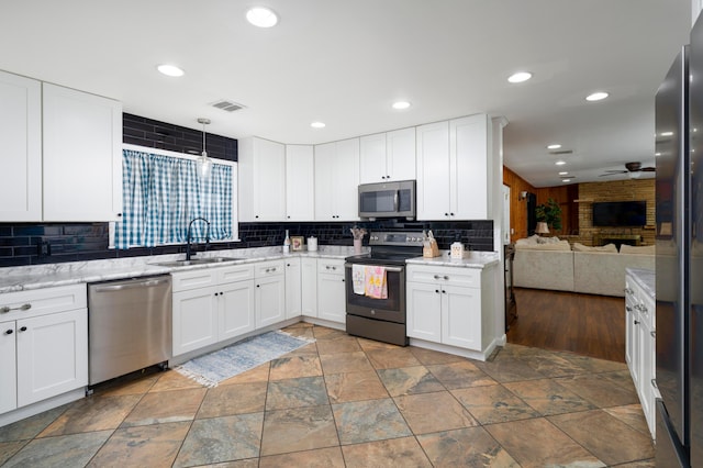 kitchen featuring sink, appliances with stainless steel finishes, white cabinets, and decorative light fixtures