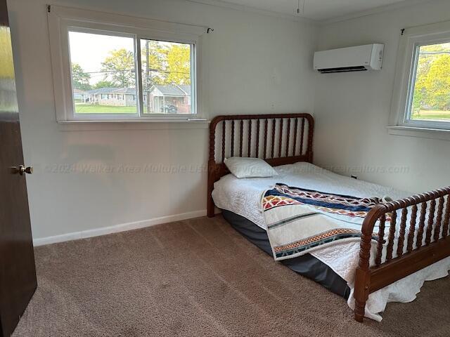 1807 30th St, Haleyville, AL 35565 - carpeted bedroom with a wall unit AC, baseboards, and crown molding