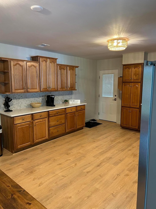 1728 Primrose Dr, Cullman, AL 35055 - kitchen featuring open shelves, brown cabinets, light wood-style floors, light countertops, and freestanding refrigerator