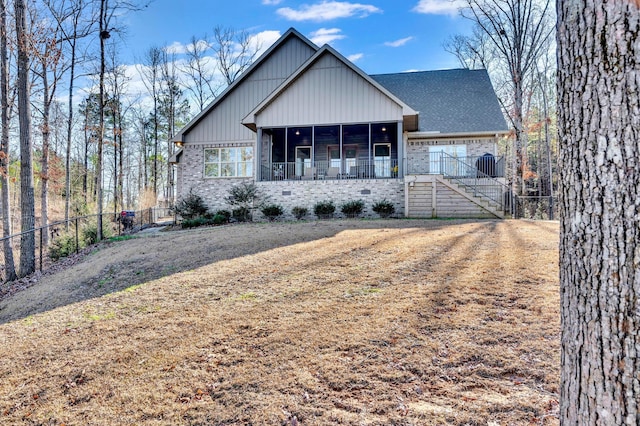 view of front of property featuring a fenced backyard, a sunroom, brick siding, a shingled roof, and board and batten siding
